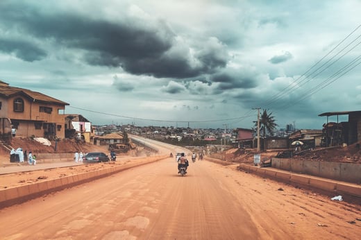 Carretera de una ciudad africana con una moto y cielo nublado